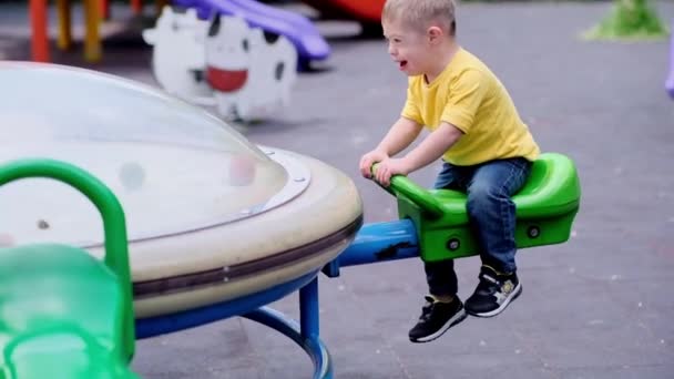 Cute Little Boy Zespołem Downa Próbuje Nowoczesny Plac Zabaw Huśtawka — Wideo stockowe