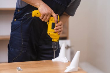 Profesyonel mobilya montajı ve tamir çalışanları ahşap dolaba bacaklar ekleme ve ahşap malzeme karlı mobilya işi ile çalışan tornavida uzmanı