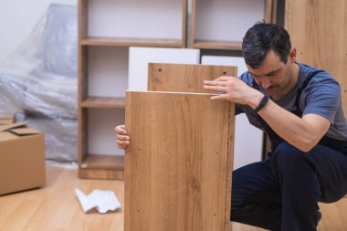 Özel mobilya teslimatı ve montajı. Kaliteli ahşaptan yapılmış tahtaları kontrol ediyor. Ofis içi marangozluk endüstrisi için rafları monte etmeye hazır.