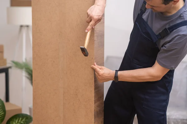 家具业主将钉子钉在衣橱后面的木板上 用专业的工具修理预制家具 — 图库照片