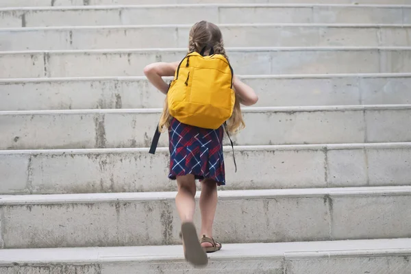 Uczennica Kolorowe Sukienki Jasnożółtym Plecakiem Idzie Szkoły Dziewczynka Długimi Warkoczami — Zdjęcie stockowe