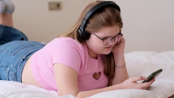 Soustředěná Dospívající Dívka Sluchátkách Poslouchá Podcast Při Psaní Zpráv Kamarádce — Stock video