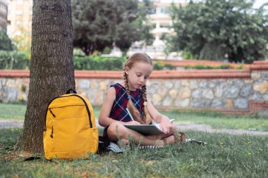Mutlu, genç bir öğrenci, doğaya bağlı, bir ağacın altında okuyor. Bu çalışkan öğrenci güneşli bir sonbahar gününde verimli bir şehir parkında öğrenmeyi kucaklıyor.. 