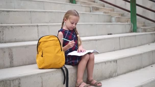 Sarışın Küçük Kız Sırt Çantasıyla Okul Stadyumunda Taş Basamaklarda Oturuyor — Stok video