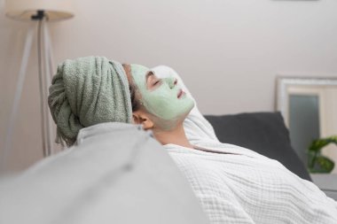 Kanepe Sığınağı: Bornozuyla sarmalanmış, rahat bir koltuğa uzanmış, spa seansı sırasında yüz nemlendirici bir maskenin sükunetini kucaklıyor.. 