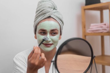 Deri Gençleştirme: Yüzünü nemlendirici bir maskeyle şımartıyor, canlandırılmış, parıldayan derisini evde gösteriyor. 