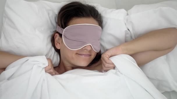 睡觉时 戴着睡眠面具的女人睡在柔软的枕头上 愉快地在床上拉毛毯 — 图库视频影像
