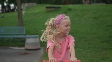 Saçlarını sallayan mutlu küçük kız yazın tahterevalli gibi geziyor. Şehir parkında çocuk eğlence parkında geziniyor. Güzel kız öğrenci şehir bahçesinde dinleniyor.