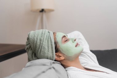 Huzurlu İnziva: Bornozla, rahat bir koltukta yüz nemlendirici bir maskeyle, evini huzurlu bir spa cenneti haline getiriyor.. 