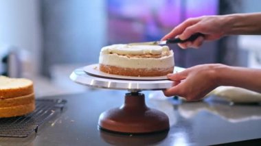 Deneyimli bir yemek blogcusu, yemek fırçasıyla pişmiş katmanları karalayan siyah önlüklü kadına organik ev yapımı pasta yapma sürecini gösteriyor.