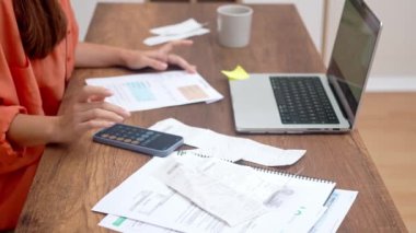 Ödeme makbuzlarıyla donanmış bir bayan güvenilir bilgisayarını kullanarak evdeki faturaları internetten ödüyor.