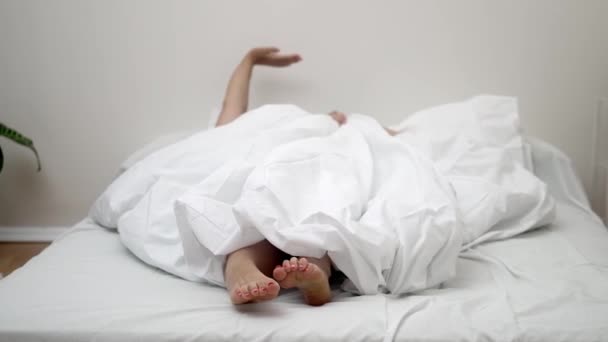 醒来的喜悦 当她醒来躺在床上时 赤着脚从毯子里探出头来 愉快地伸展着身体 — 图库视频影像