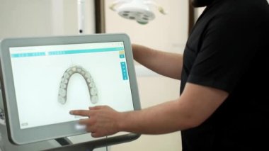 Sakallı dişçi ekranda insan çene modellerini gösteriyor öğrenciler için ders veriyor ve tıp merkezinde yenilikçi diş tedavisi teknolojisi sunuyor