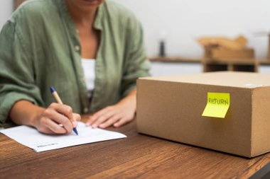 Kadın paketin yanında sarı etiketli teslimat hakkında şikayette bulunuyor. Alıcı, geri gönderme arzusuyla aldığı mallardan memnun değil.