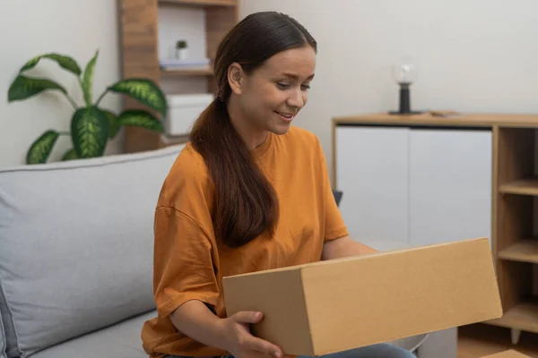 Digital Retail Happiness: Enjoying her couch, a woman showcases her online order delivery, exemplifying the comfort of receiving goods at home.