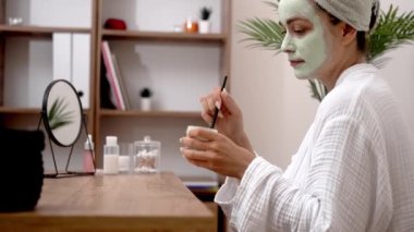 Cilt bakımı: Havluya sarılı banyo yaptıktan sonra, yaşlanmayı önleyen, su alan ve kusursuz cilt için ustalıkla bir maske takıyor.. 