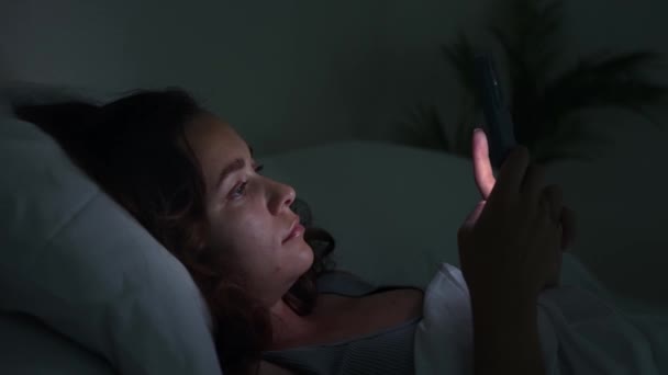Geceleri Kadın Yatakta Uzanıyor Telefon Ekranı Tarafından Tüketiliyor Uykusuzluk Akıllı — Stok video