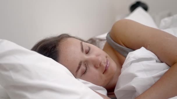 在一个宁静的卧室里 一个年轻的女人睡在舒适的骨科床垫上的白色毛毯下 睡得很香 — 图库视频影像