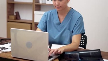 Genç doktor bilgisayardan hastaya röntgen sonuçlarından bahsediyor. Kadın tedavi planını tartışıyor ve tavsiyelerde bulunuyor.