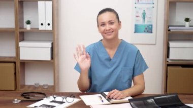 Dijital Sağlık Uygulayıcısı: hasta belgeleriyle, kadın doktor el sallayarak online tıp çağını anlatıyor. 