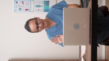 Çevrimiçi Danışmanlık: Teletıp seansında mavi labaratuar önlüklü doktor, internet üzerinden hastaya dostça el sallıyor ve göz teması kuruyor.. 