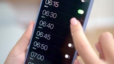 Alarm uygulaması teknolojisini kullanarak akıllı telefondan uyanmak için alarm saatini ayarlayan kadın parmaklarını kapat 