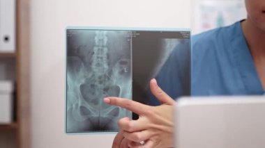 Kadın doktor internetteki randevusunda hastayla uzaktan konuşuyor. Diz üstü bilgisayarlı kadın, uzaktan kumandalı tıbbi hizmetlerin nedenlerini açıklayan röntgen filmlerini işaret ediyor.