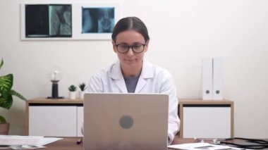 Genç bayan doktor, hasta organlarının incelenmesini dizüstü bilgisayardaki tıp uzmanlarının çalışma masasında resimlerle ve belgelerle birlikte modern klinikte inceledi.