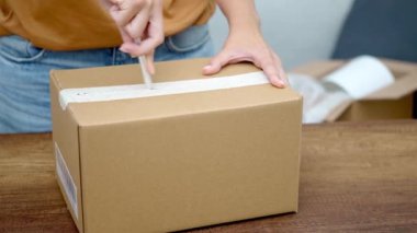 Genç bir bayan paket açmak için bıçak kullanıyor. Karton kutunun kutusunu açıp, online alışveriş yapıyor.. 