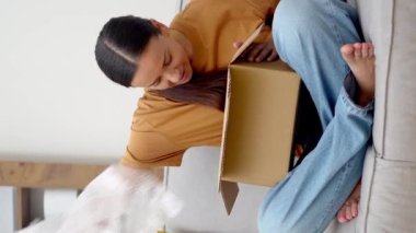 Siber Perakende Serenity: Kanepesinde, memnun bir bayan paketini açıyor, çevrimiçi alışveriş başarısı ve nakliye sayesinde mutluluk yayıyor.. 