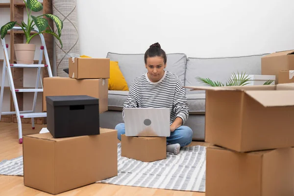 Woman Her New Space Surrounded Boxes Uses Laptop Plan Home — Stock Photo, Image