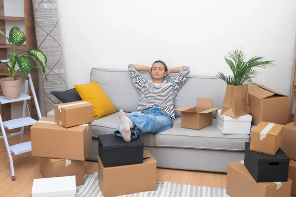 exhausted relocation, tired woman lean on sofa, surrounded by unpacked boxes, real estate journey and the transition to her new home