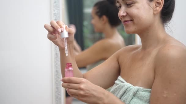 クローズアップ 女性は 自宅で 彼女の鏡の近くの彼女のアンチエイジングスキンケアのためにヒアルロン酸を適用するために血清ドロッパーを使用します — ストック動画
