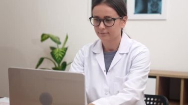 Teletıp Uzmanı: kadın doktor, tıbbi destek sağlamak ve video danışmanlık yapmak için bilgisayarına bağlanıyor..