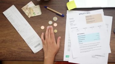 Finans Organizatörü: Yukarıdan bir kadın, aile bütçesini etkin bir şekilde yönetiyor, harcamaları hesaplıyor ve faturaları ödemek için para ve sikkeleri sayıyor 
