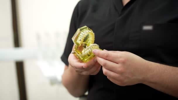 Стоматолог Черной Форме Держит Искусственные Человеческие Челюсти Металлическими Зубными Скобками — стоковое видео