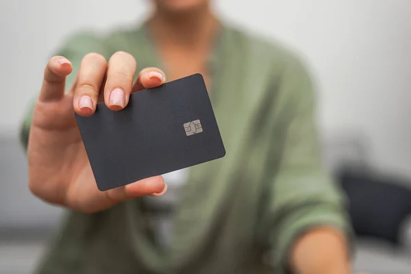 A close-up reveals a ladys hand displaying a dark credit card with a chip, ideal for contactless payments, illustrating online shopping and mobile banking.