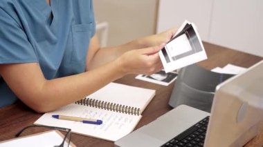 Teşhis Ultrasonu: Doktor mavi önlüğüyle ultrason görüntülerini gözden geçirir ve kapsamlı hasta kayıtları için laptopunda titiz notlar tutar..