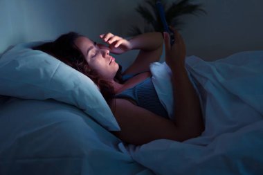 Uykusuzluk ve dijital bağımlılık pençelerinde genç bir bayan gece boyunca akıllı telefonlarının parıltısına sığınıyor.