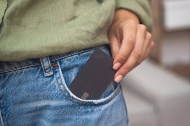 Çabasız modern alışveriş: Bir bayan uygun online ödeme için kot pantolonunun cebinden koyu renk çipli bir kredi kartı alıyor, alışveriş yapmanın ve ödeme yapmanın kolay bir yolu. 