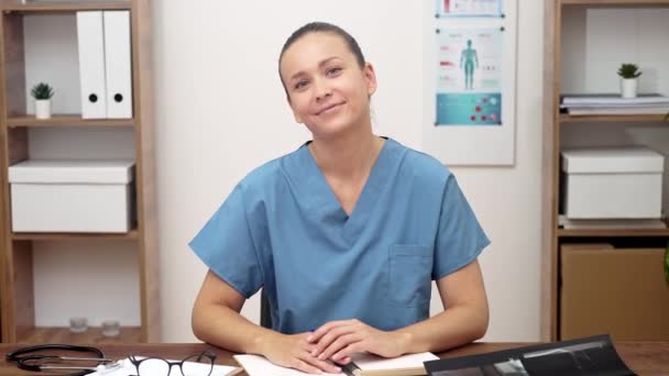 Mavi Üniformalı Bir Doktor Masasında Gülümseyen Bir Kamera Tıbbi Belgeler — Stok video