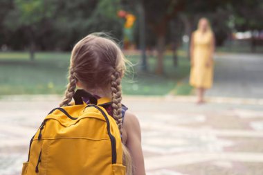 Okul çantalı, neşeli kız koşucularıyla okul çıkışında annesini bekle ve onunla şehir parkında buluş. Oyuncu buluşmaları, aile ilişkilerinin gücünü simgeliyor.. 