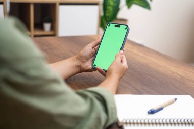 Genç bir kadın cep telefonuyla alışveriş yapıyor oturma odasındaki masada oturuyor. Yakın plan bir bayan akıllı telefon ekranına bakarak online alışveriş yapıyor.