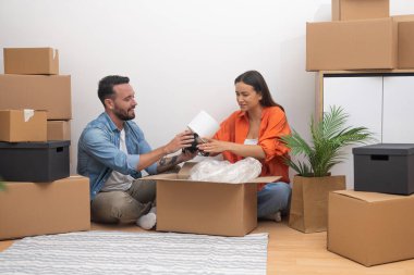 Neşeli genç çift yeni evlerinde kutuları taşımaktan bir lamba toplarken mutlu bir şekilde boks yapıyor. Yeni bir başlangıç, taşınma ve aile saadeti.