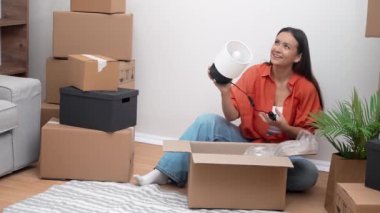 Çekici bir kadın, yeni evde, yeni taşınan mobilyaların bütünlüğünü incelemek için kırsal kesimdeki yeni eve büyük paket kutularını açar.