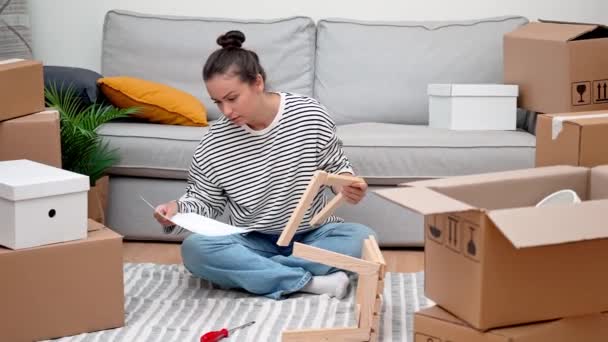 Žena Uprostřed Stěhujících Kartonových Krabic Nábytku Sedí Podlaze Aby Sestavila — Stock video