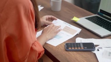 Kadın, evde hesap makinesine ev harcamaları finansmanı hesaplıyor. Ev odaklı eş, dizüstü bilgisayarla aile finansmanı veya bütçe yönetimine ilişkin fatura vergisi ödüyor.