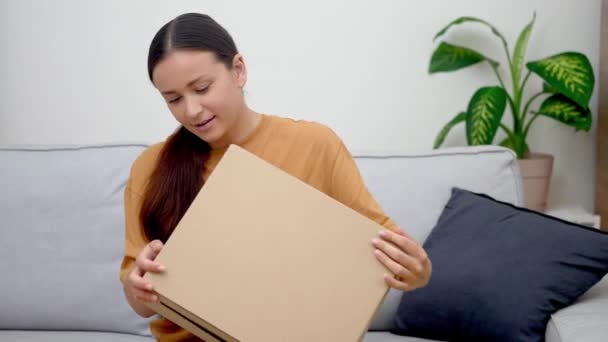 彼女のソファの女性 オンライン購入からパッケージを受け入れる 家の配達の利便性を高く評価 — ストック動画