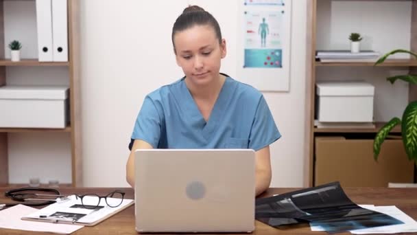 オンライン医療相談 彼女のラップトップで作業 女性医師は仮想医療援助を提供し ビデオ会議を実施し テレヘルスのコンセプトを象徴しています — ストック動画