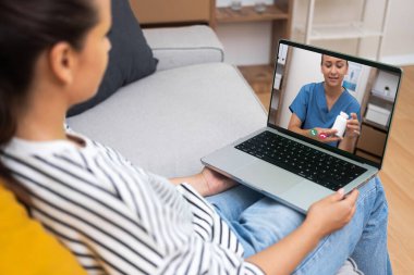 Kadın doktor, bir video görüşmesi ile bir hastaya ilaç tedavisi uyguluyor. Modern teletıp uygulamalarını örnek alıyor..